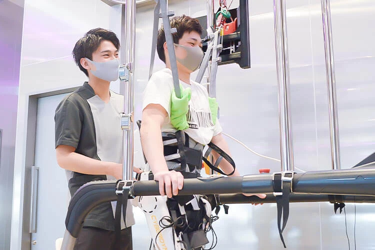 九州再生医療センターのリハビリ施設でトレーニングを行う患者とスタッフ